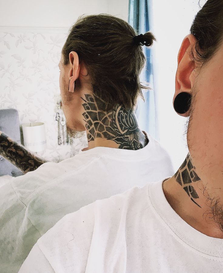 a woman with tattoos on her neck looking at herself in the mirror