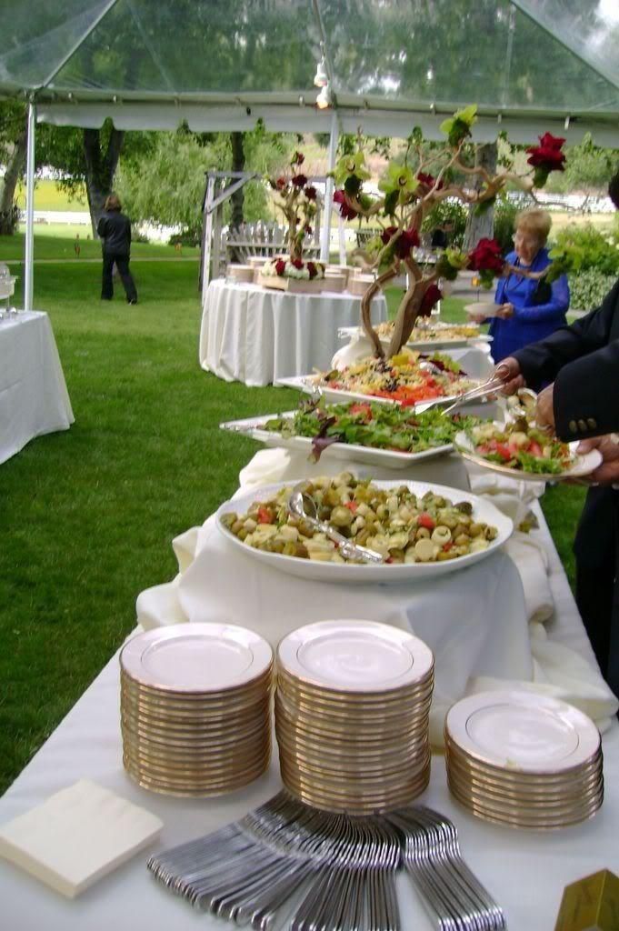 a buffet table with plates and silverware under a tented area for people to eat