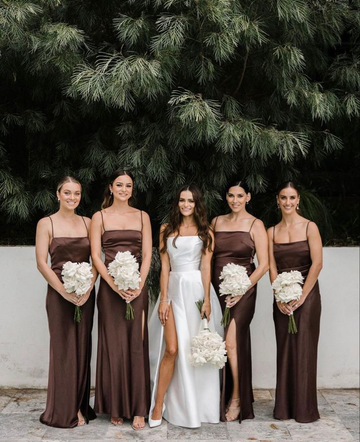 the bridesmaids are wearing brown dresses and holding bouquets with white flowers on them