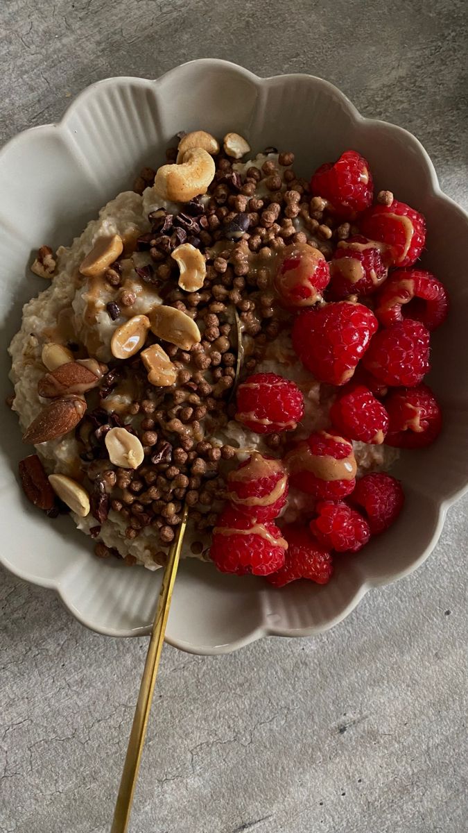 a bowl filled with oatmeal and raspberries on top of a table