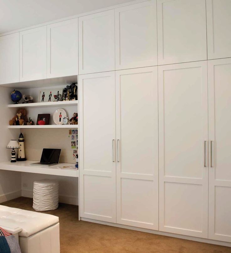 a bedroom with white cupboards and shelves in it