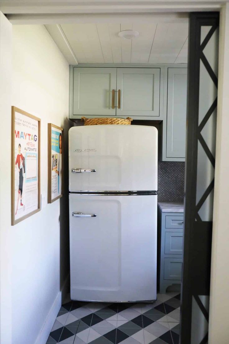 a white refrigerator freezer sitting inside of a kitchen next to a wall with pictures on it