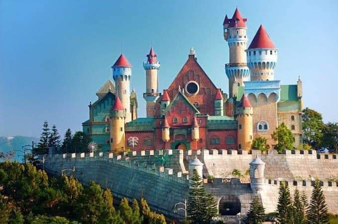 the castle is built on top of a hill with trees around it and blue sky in the background