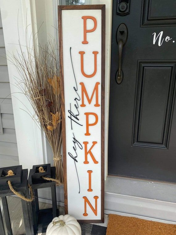 a wooden sign that says pumpkin on it next to a potted plant and door