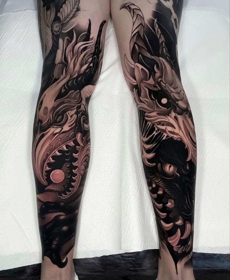 the legs and ankles of a woman with dragon tattoos on her body are covered in black ink