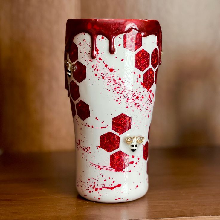 a red and white vase sitting on top of a wooden table