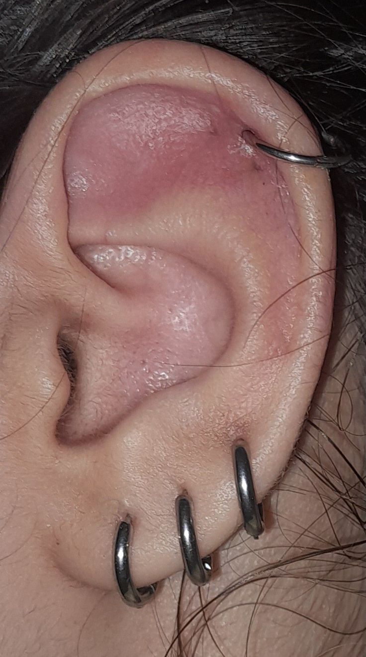 a woman's ear with three metal hoops attached to the side of her ear