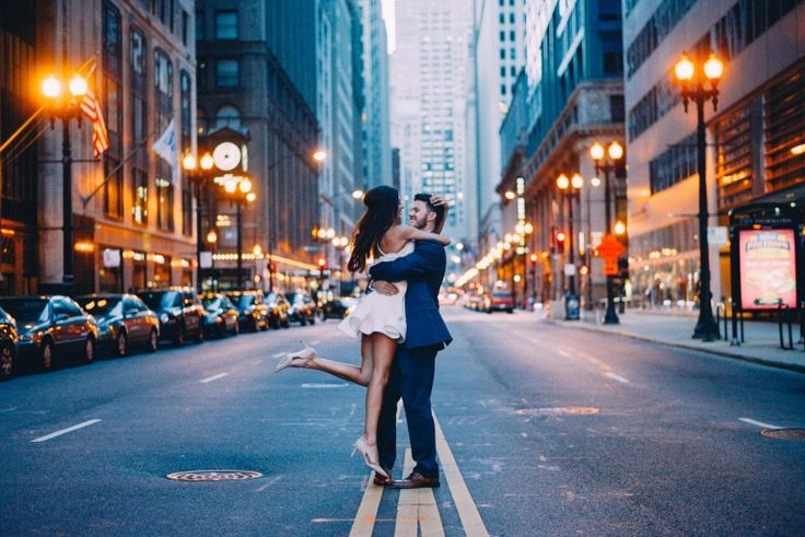 a man and woman hugging in the middle of an empty city street with tall buildings