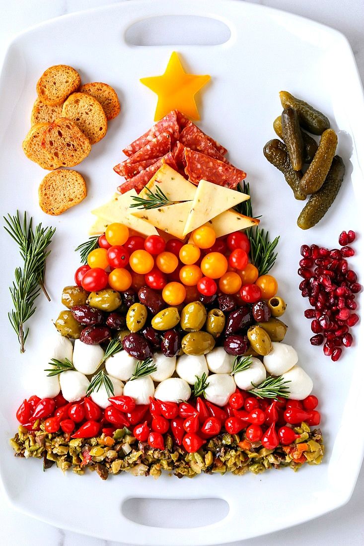 a christmas tree shaped platter with olives, tomatoes, cheese and crackers