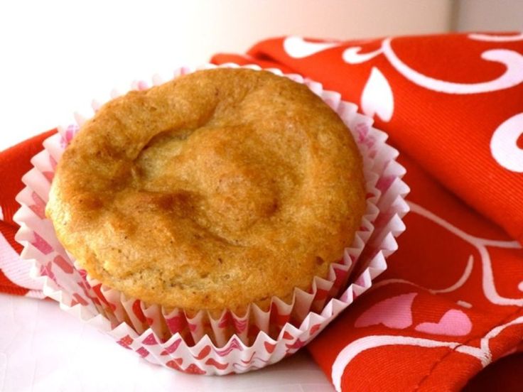 a muffin sitting on top of a red and white cloth next to a cup