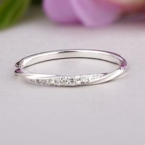 a white gold wedding band with three diamonds on the side, and a pink flower in the background