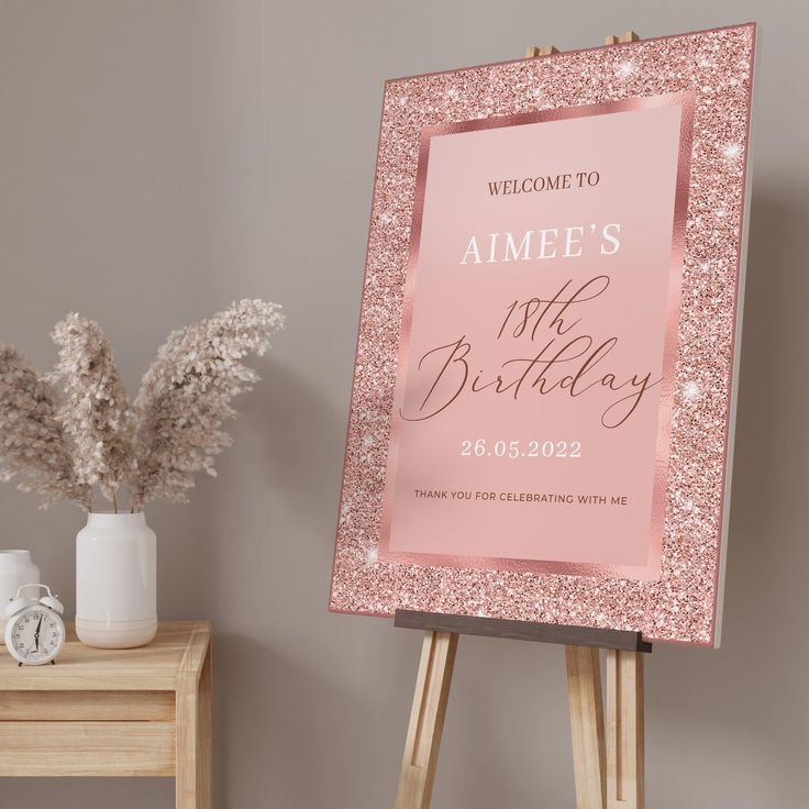 a pink birthday sign sitting on top of a wooden easel next to a vase with flowers