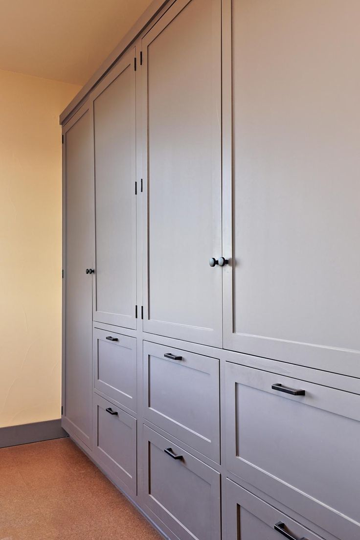 a large white closet with many drawers and cupboards on the wall next to it