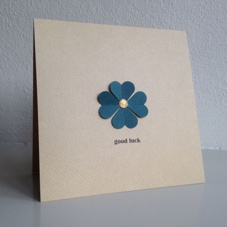 a card with a blue flower on it that says good luck and is placed in front of a white wall