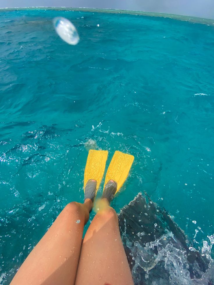 a person is floating in the water with their legs crossed and yellow paddles sticking out