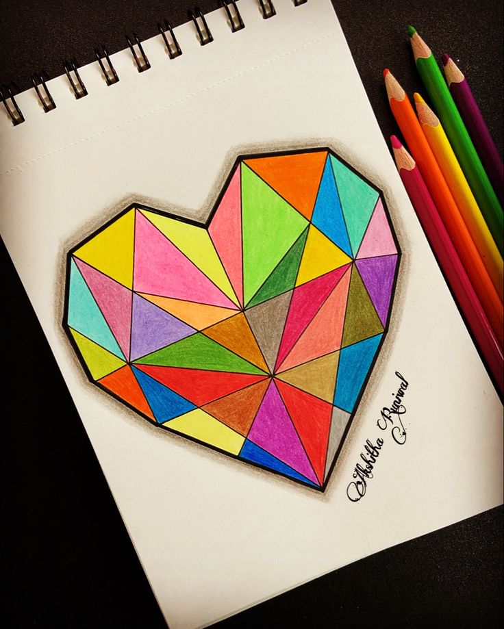 a drawing of a heart made out of colored paper with pencils next to it