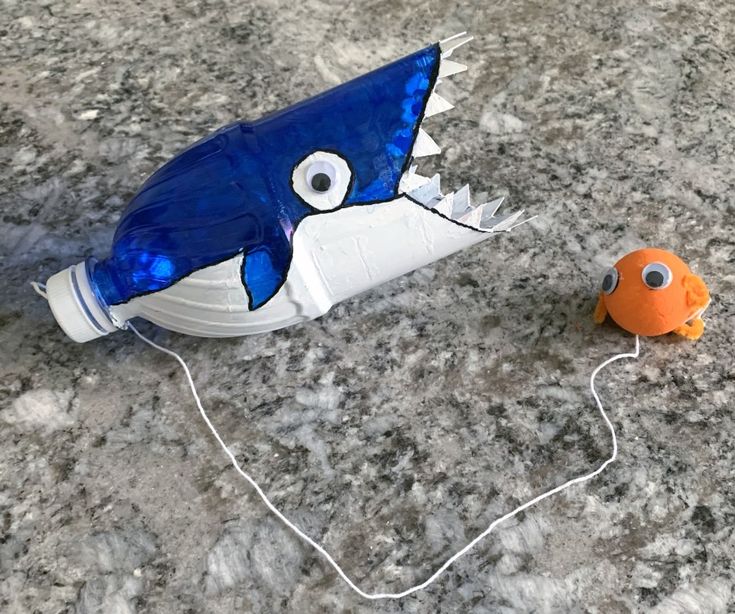 a plastic toy that looks like a shark and a goldfish are on the ground