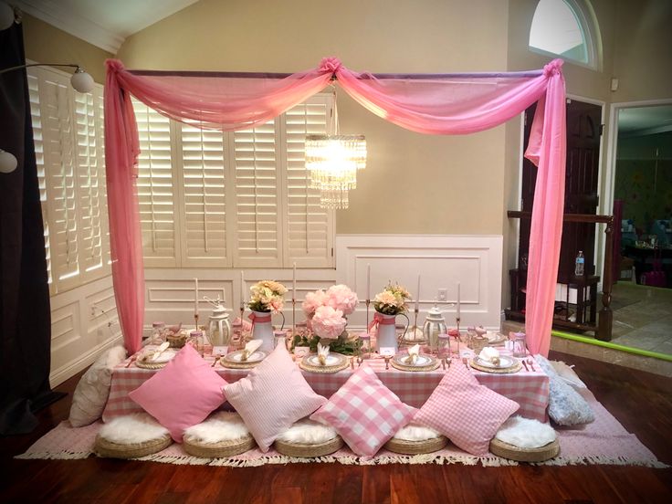 a table set up with pink and white pillows