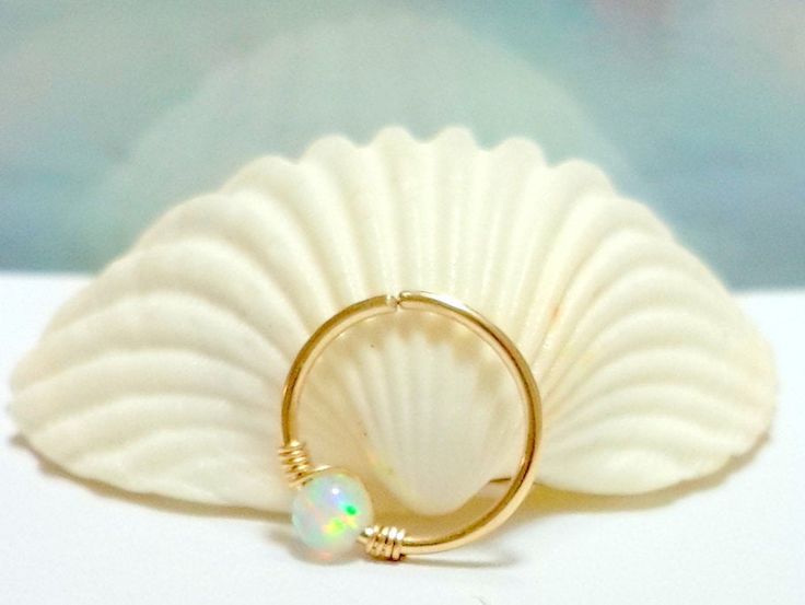 This listing is for ONE earring handcrafted 14K gold filled hoop with lab created White Fire Opal bead, wrapped with gold filled wire . Extremely comfortable, good for everyday use. Metal:14K Yellow Gold Filled or 925 Sterling Silver Gauge (Thickness): 16 Gauge (1.2mm), 18 Gauge (1mm),20 Gauge (0.8mm), 22 Gauge (0.6mm) Diameter:7mm-tiny, 8mm, 9mm, 10mm, 11mm Opal:Fire White Opal 3mm Select your preference in the Gauge & Inner Diameter and Material options at the top right of this page. HOW T Opal Cartilage Earring, Opal Septum, Helix Ring, Tragus Ring, Opal Nose Ring, Tragus Hoop, Tragus Piercing Jewelry, Septum Nose Rings, Cartilage Earring