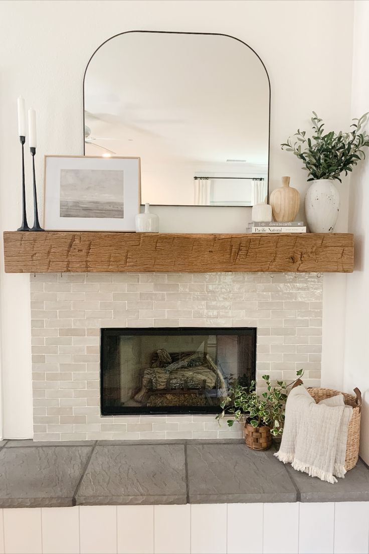 a fireplace with a mirror above it and some plants on the mantels in front of it