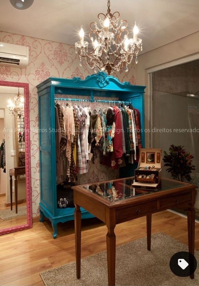 a blue cabinet with clothes hanging on it and a chandelier in the background