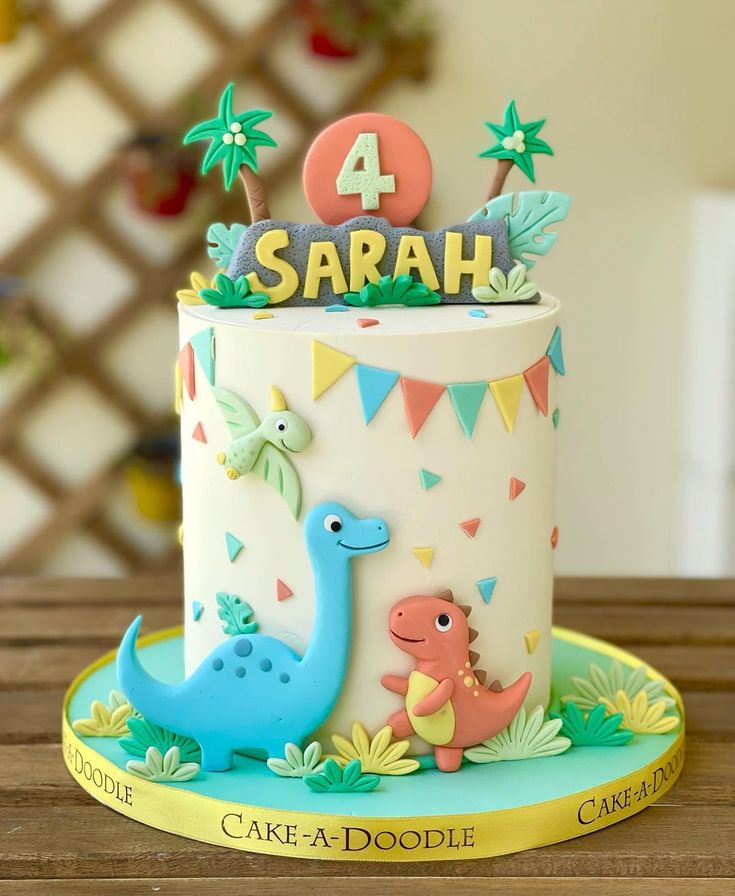 a birthday cake with a dinosaur on it and the number four in the top tier