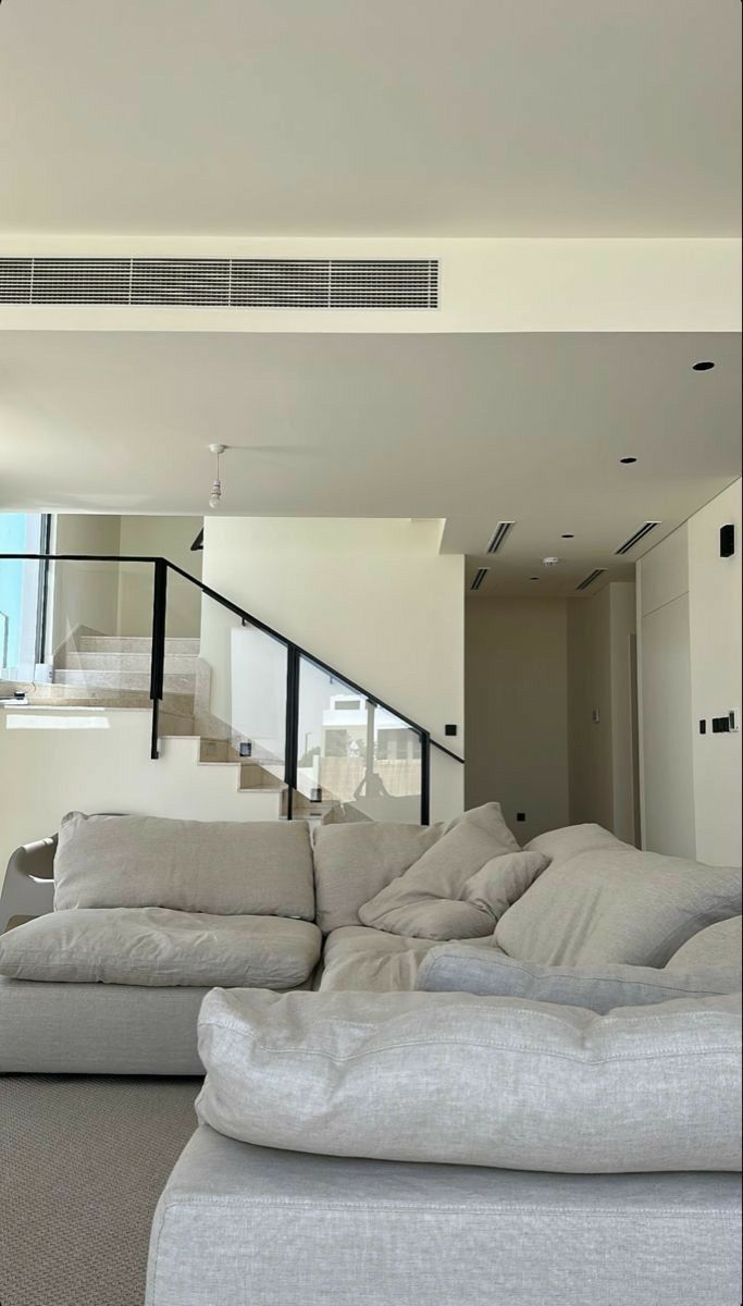 a living room filled with lots of furniture next to a stair case in the background