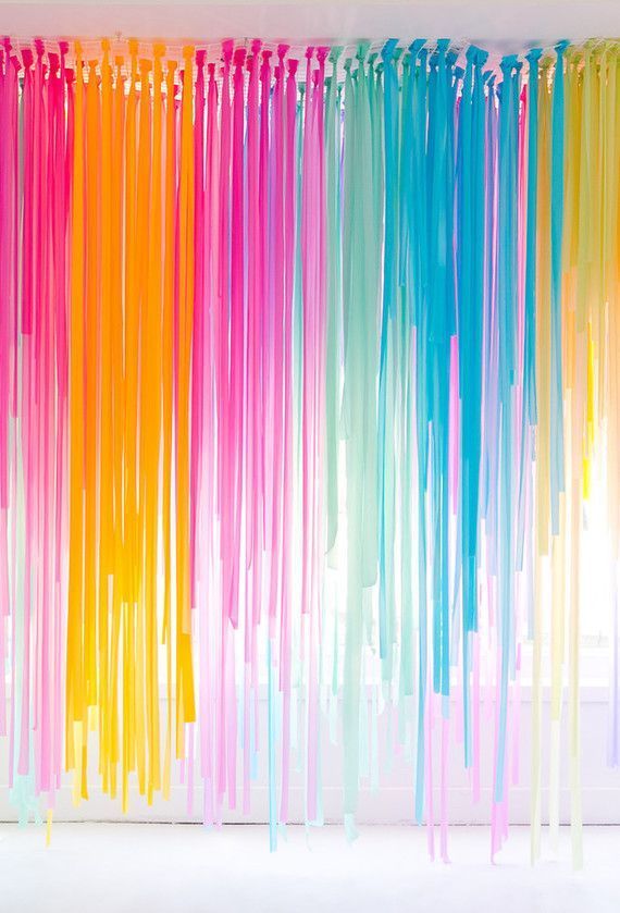 multicolored streamers hanging from the ceiling in front of a white wall and window