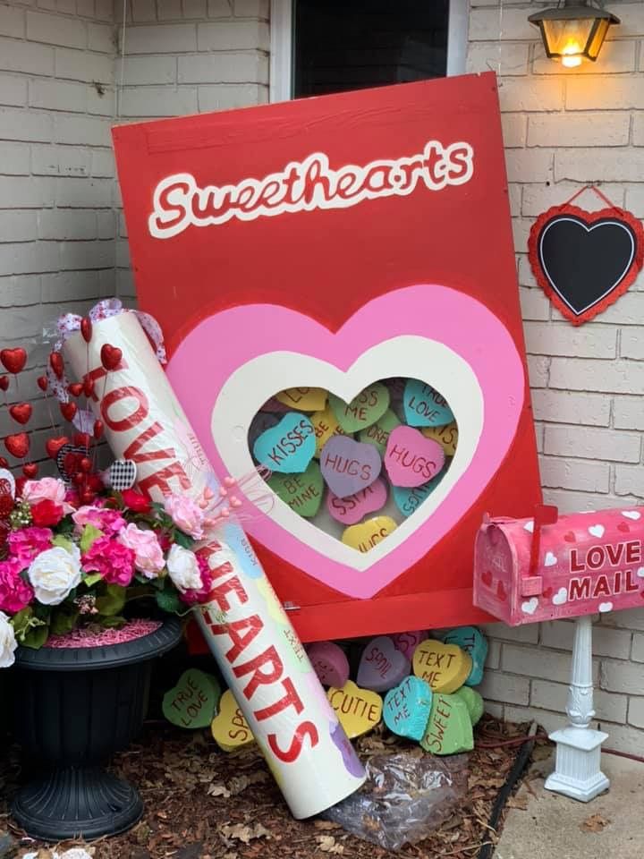 a valentine's day sign with candy and flowers in front of it that says sweethearts