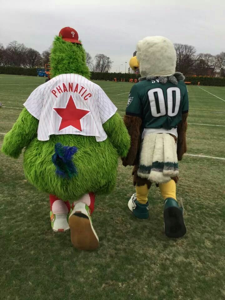 two people dressed in mascot costumes walking on the field with one person wearing a football uniform