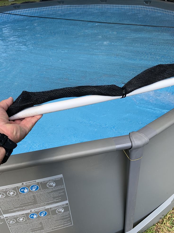 a person is holding an object over the edge of a swimming pool