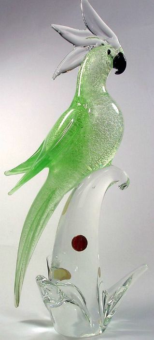 a green glass bird sitting on top of a white object