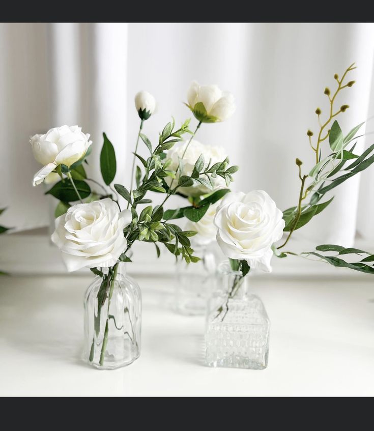 three clear vases with white flowers in them