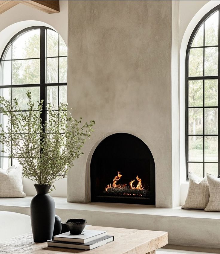 a living room filled with furniture and a fire place in front of two large windows