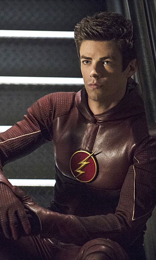 the flash is sitting on some steps in his leather outfit and looking at the camera