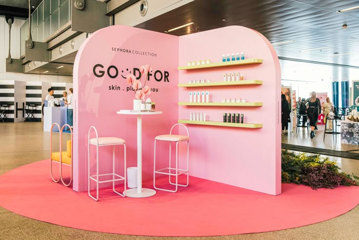 a pink display with shelves and stools on the floor in front of it that says go for