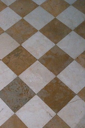 a white and brown checkered tile floor with rust stains