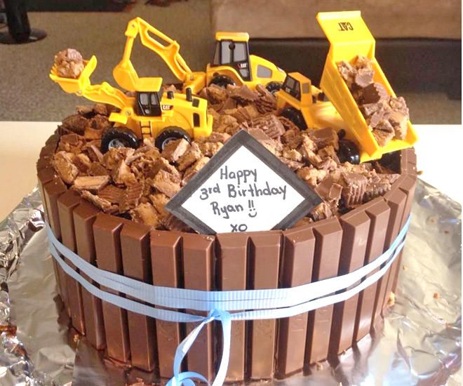 a birthday cake with chocolate frosting and construction vehicles on top