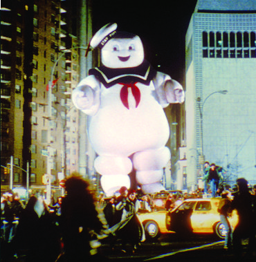 a large inflatable character is being paraded down the street with other people