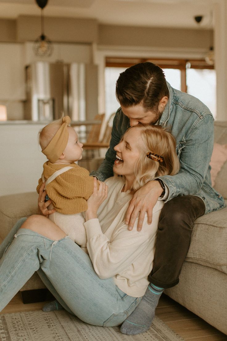 a man and woman are sitting on the floor with a baby in their lap,