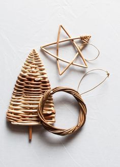 three wooden ornaments are arranged on a white surface, one is shaped like a christmas tree and the other is made out of wood sticks