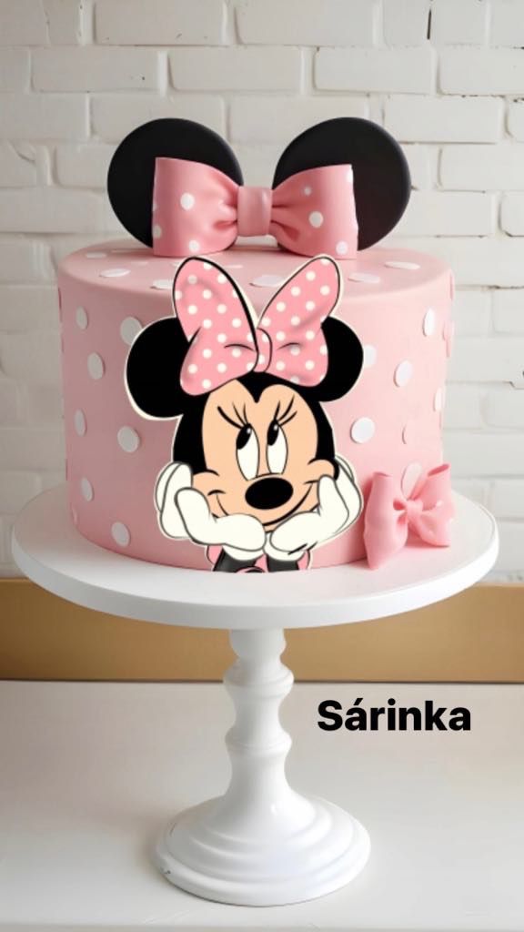 a pink minnie mouse cake with polka dots and a bow on top, sitting on a white pedestal