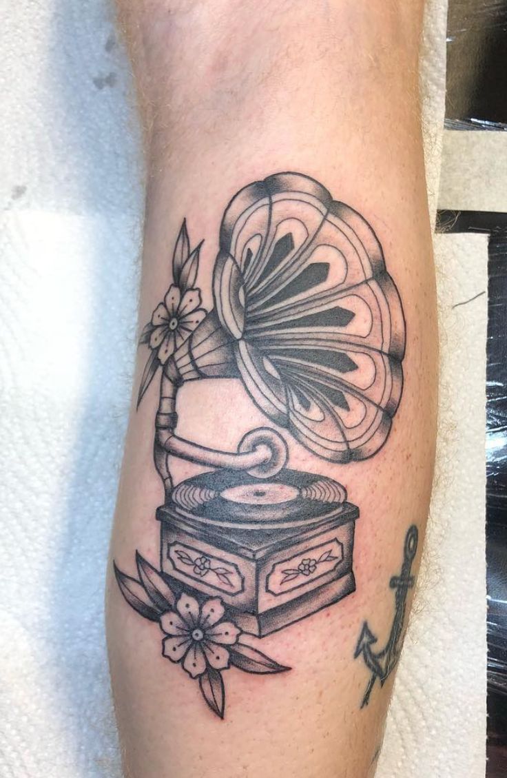 a tattoo on the leg of a person with a record player and flowers in it