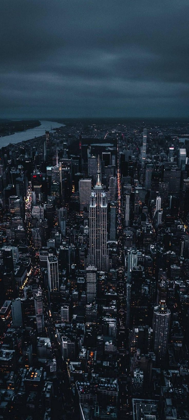 an aerial view of a city at night with the lights on and dark clouds in the sky