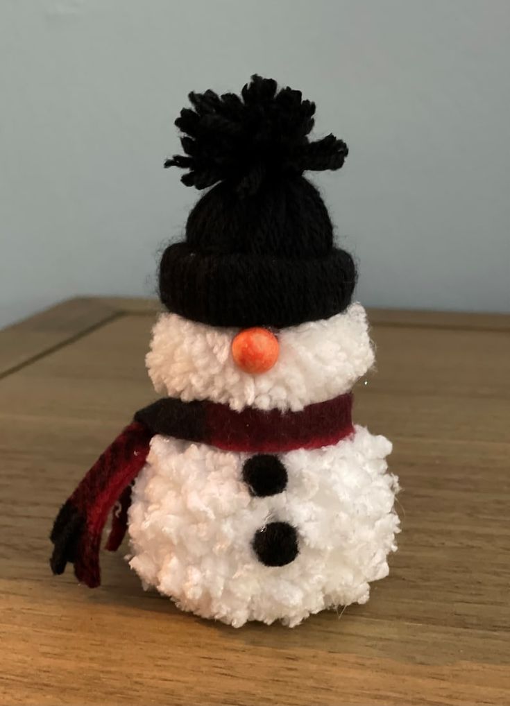 a snowman made out of pom - poms sitting on top of a wooden table