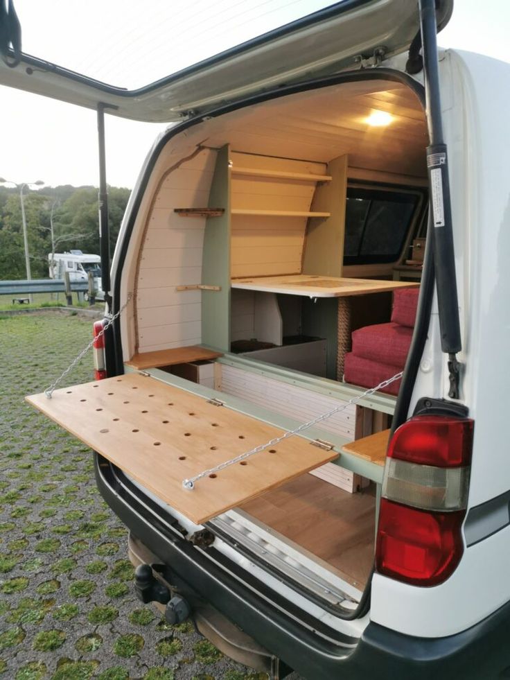 the back end of a white van with its doors open and shelves in the trunk