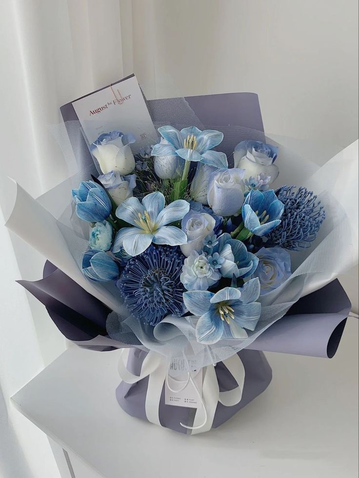 a bouquet of blue and white flowers with a card