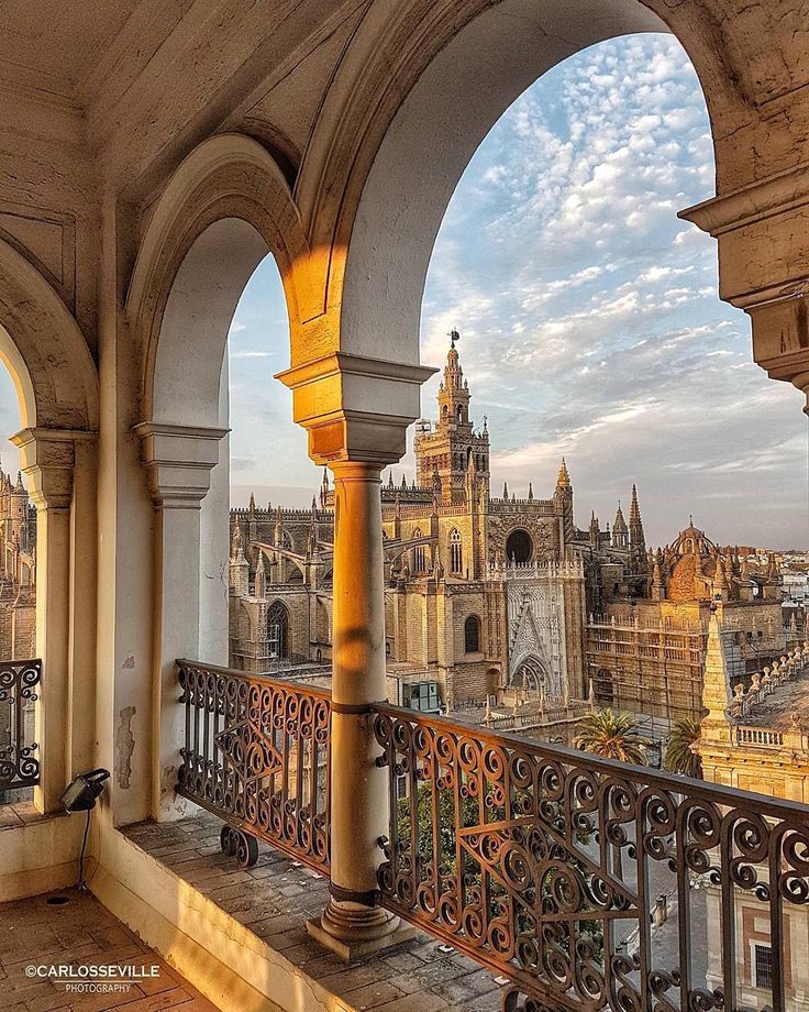 an ornate balcony overlooks the cityscape and castle like building in the distance