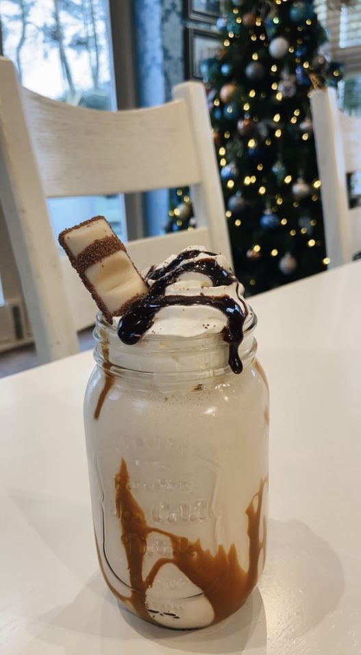 a glass jar filled with chocolate and marshmallows on top of a table