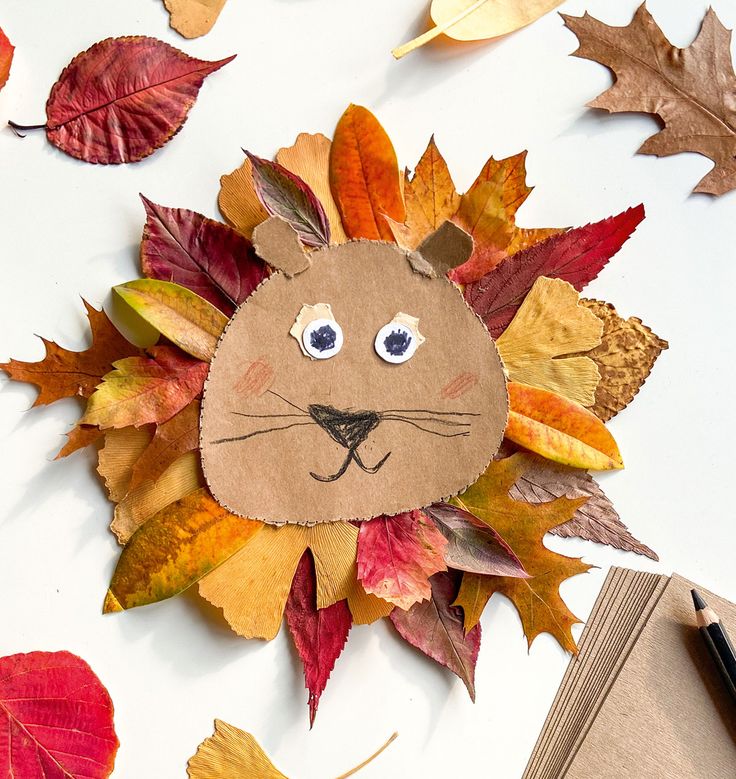 a lion made out of leaves on top of a table with a book and pen